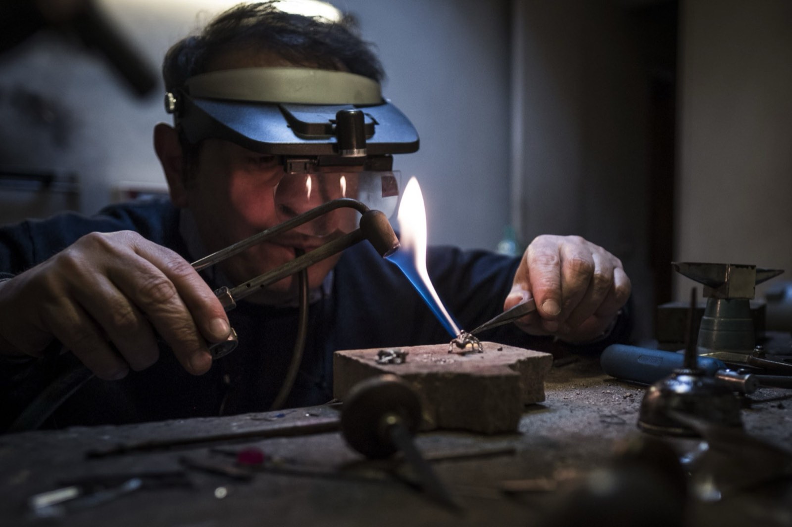 A goldsmith soldering at the bench in the Gisci workshop